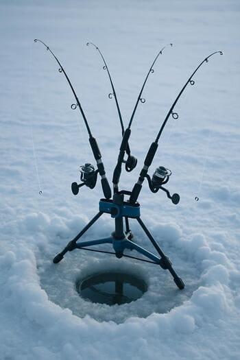Невысокая стойка с несколькими зимними удочками на льду