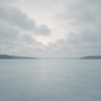 Мягкие облака тянутся полосой над замёрзшим озером в спокойную погоду