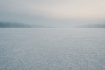 Пустое замёрзшее озеро в утренней дымке без следов на льду