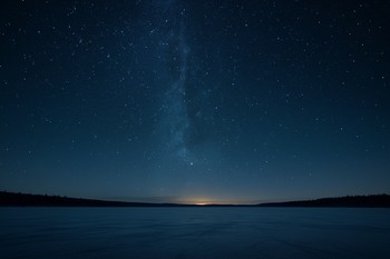 Звёздное небо над линией горизонта и замёрзшим озером